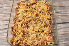 a casserole dish with meat, cheese and bread in it on a wooden table