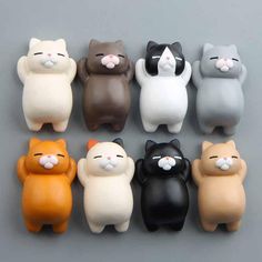 small plastic cat figurines sitting in a row on a gray surface with other cats behind them