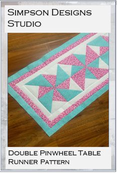 a table runner with pink and blue triangles on it, sitting on a wooden floor