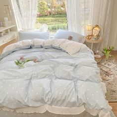 a bed with blue sheets and white polka dots on it in front of a window