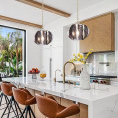 a kitchen with marble counter tops and bar stools in front of an open window