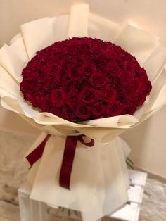 a bouquet of red roses wrapped in white paper