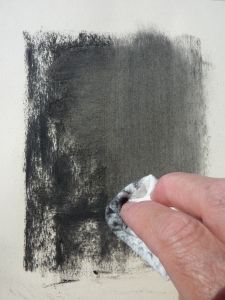 a hand holding a piece of cloth over a black and white painting