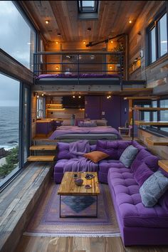 a living room filled with purple couches next to a large window overlooking the ocean