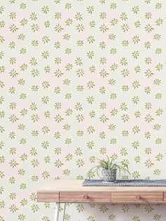 a table with a plant on top of it in front of a wallpapered background