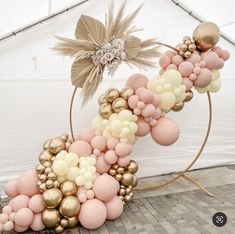 a balloon arch with gold, pink and white balloons in the shape of a flower