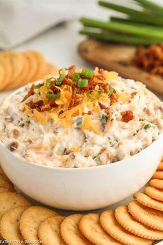 a white bowl filled with dip surrounded by crackers