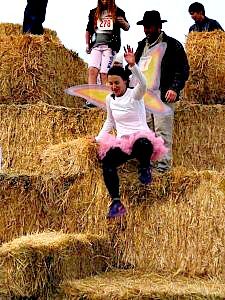 a group of people standing on hay bales with one woman sitting on the top