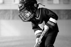 a young boy wearing a helmet and holding a baseball bat in his hands while standing on a field