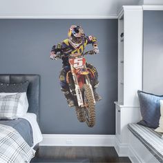 a man riding a dirt bike on top of a bed in a room with blue walls