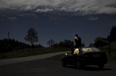 a man standing on top of a car in the dark