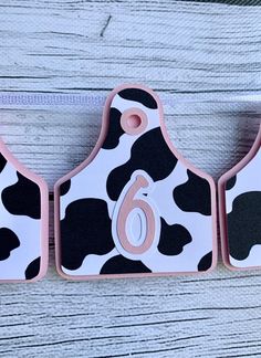 three pink and black cow print magnets with numbers on them