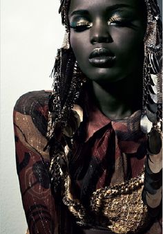 a woman with black hair and gold eyeshades is wearing an elaborate headdress