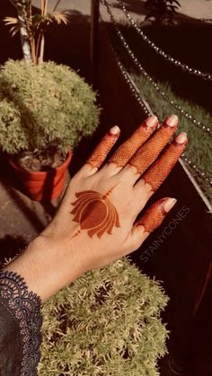 a woman's hand with hennap on it and some potted plants