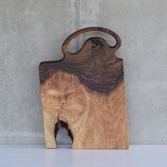 a wooden cutting board sitting on top of a white counter next to a cement wall