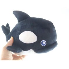 a hand holding a stuffed animal that looks like an orca whale with big eyes