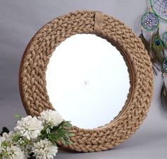 a round mirror sitting on top of a table next to white flowers and dream catchers