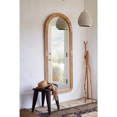 a large mirror sitting on top of a white wall next to a stool and lamp