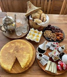 a table topped with lots of food on top of a wooden table next to cups and saucers