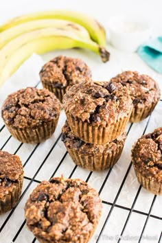 muffins cooling on a wire rack with bananas in the backgroung