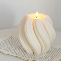 a white candle sitting on top of an open book