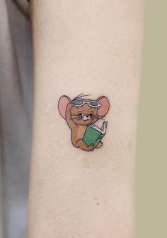 a small mouse tattoo on the left inner arm, with a book in it's hand