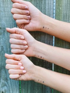 three people holding their hands together with small dots on the wrist and hand, all in different positions