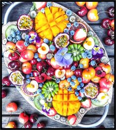 a platter filled with lots of different types of fruit on top of a wooden table