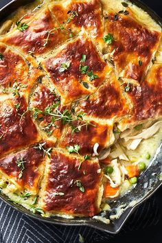 a casserole dish with meat and vegetables in it on a blue table cloth