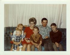 an old photo of a family sitting on a couch with two children and one adult