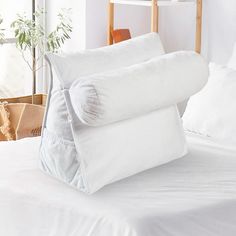 two pillows stacked on top of each other on a bed with white sheets and pillows