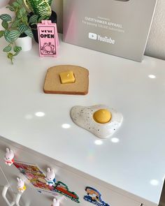 two pieces of bread and an egg on a white counter top with plants in the background