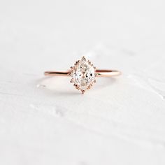 a yellow gold engagement ring with an oval cut diamond in the center on a white background