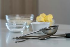 a table topped with bowls and metal utensils next to each other on top of a white counter