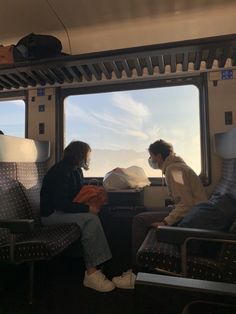 two people sitting on a train looking out the window