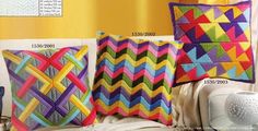 three colorful pillows sitting on top of a bed