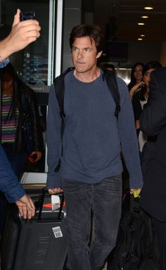 a man walking through an airport carrying a suitcase