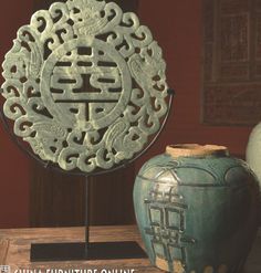 two vases sitting next to each other on top of a wooden table in front of a red wall