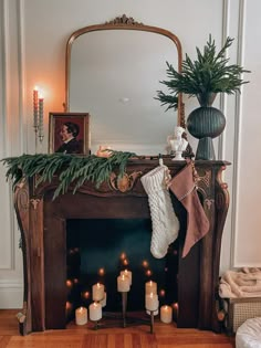 a fireplace with candles and stockings on it in front of a mirror, potted plant