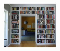 a bookshelf filled with lots of books in a living room next to a window