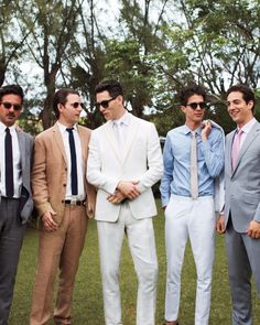 a group of men standing next to each other in front of trees wearing suits and ties