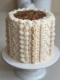 a white cake sitting on top of a plate covered in frosting and crochet