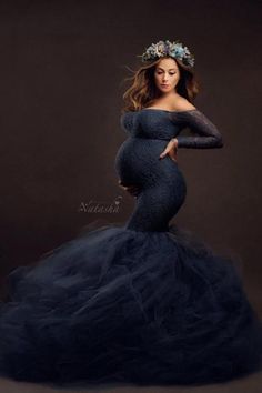 a pregnant woman in a blue gown poses for the camera with her hands on her hips