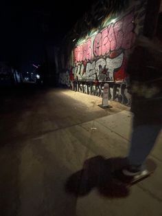 a person on a skateboard in front of a wall with graffiti