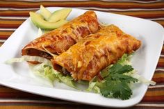 two enchiladas on a white plate with lettuce and an apple