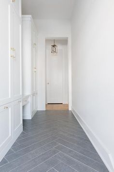 an empty hallway with white cabinets and gray flooring