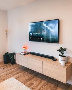 a flat screen tv mounted on the wall above a wooden entertainment center in a living room