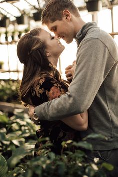 a man and woman kissing in a greenhouse