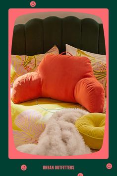 an orange pillow on top of a bed with green headboard and pink frame around it