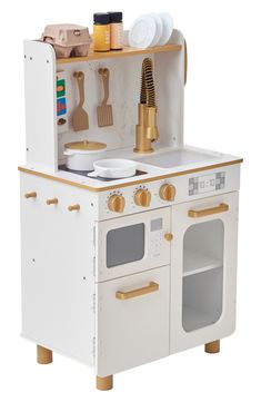 a white wooden play kitchen set with lots of cooking utensils on top of it